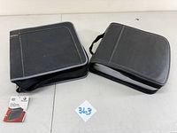 Two black CD binder books with handles and zippers on a white surface