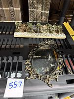 Ceramic plaque of houses shown on a black shelf along with the gold mirror also shown