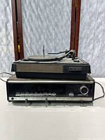 Front and top view of Channel Master Model 6603 turntable sitting on top of the receiver. Shows wood grain sides and tonearm.