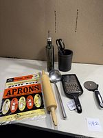 Cooking utensils arranged on table with apron and labeled lot number