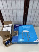 Boxed nebulizer with instruction manual visible, blue sneaker glides separated in a smaller open box, and boxed shower stool with product photo on the packaging.
