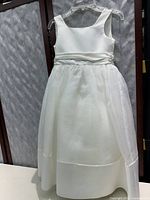 Front view of white sleeveless girls dress with tulle skirt and ribbon waist