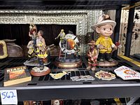 Firefighter figurines and fireshield stained glass decoration along with small patches and book on shelf