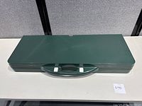 Folded green plastic carrying case with handle, compact and portable.