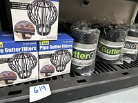 Photo showing three boxes of 2-pack Pipe Gutter Filters stacked alongside multiple rolls of gutter guards wrapped in plastic.