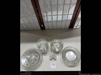 Top down view of plates, bowls, and salt and pepper shakers showing clear glassware with textured pear pattern and round shapes.
