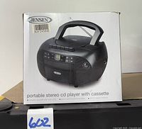 Box with image and branding of Jensen portable stereo with CD player and cassette deck, showing front and top handle.
