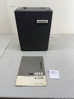 Front view of black Lafayette RK-137A tape recorder case with manual on table in front