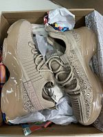 Pair of blush color knitted sneakers with decorative crystals and thick beige glossy sole in shoe box with tissue paper