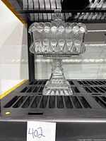 Full view of the Jeanette glass wedding cake box on black shelving.