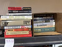 Stack of assorted military books showing titles and authors on spines and covers.