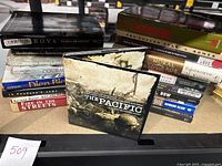 Stack of assorted military and historical used books and one DVD titled The Pacific with an image of a battlefield on the cover.