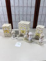 Three Precious Moments figurines displayed with their original boxes behind them on a table, showing overall lot layout and packaging condition