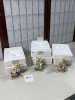 Three Precious Moments Guardian Angels figurines displayed with original styrofoam boxes behind them on a table.