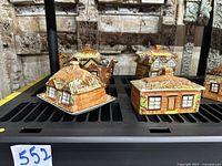Full view of four small and medium cottage ware containers with detailed thatched roofs and windows.