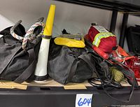 Photo showing three black bags side by side; coiled ropes visible, yellow and white small safety cone, and red first aid pouch visible on top