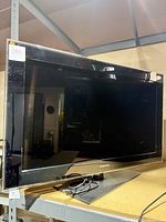 Front view of Samsung 40-inch black TV showing screen and brand logo with power cord on shelf.