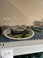 Side view of silver plated scalloped tray on a green and white plate with spoons laid beside it