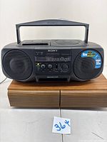 Front view of Sony CFD-V20 boombox with visible speakers, cassette deck, radio tuner, control knobs, and handle.
