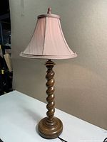 Full view of the lamp showing the spiral wooden base and fabric shade shape and color.