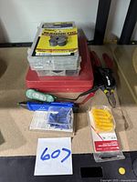 Full view of electrical tools, pliers, testers, and assorted boxes of springs and O-rings arranged on surface.