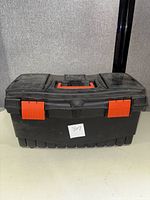 Closed black plastic toolbox with two red latches and a handle on top.