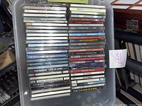 Stack of assorted used music CDs in jewel cases, showing titles by Neil Diamond, Tom Petty, Josh Groban and others.