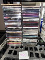 Front stack of assorted used music CDs showing titles and artists including Eric Clapton, Johnny Cash, The Zombies, and more.