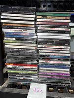 Photo showing a stack of assorted used music CDs with titles visible including Michael Jackson's Number Ones, Peter Wolf's A Cure for Loneliness, and holiday music collections.