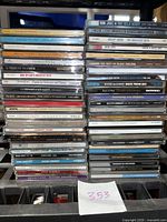 Photo showing stacks of assorted used audio CDs with visible artist names and titles such as Bon Jovi, Cheap Trick, Celine Dion, Sheryl Crow, David Crosby, and others.