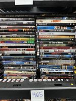 Photo of used DVD lot showing titles stacked in multiple rows with visible spine titles.