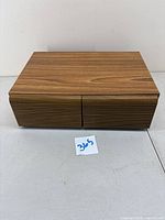 Wooden VHS tape holder with horizontal slatted front on a white surface