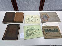 Top down view of six vintage books and souvenir travel prints including Little Journeys books and Johnstown Horror book, arranged on a table.