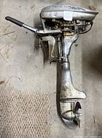 Side profile of vintage Champion outboard motor showing entire length including propeller and handle.