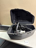 Vintage Sears Craftsman chainsaw stored inside open black hard plastic carrying case on white surface.