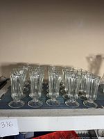 Photo showing all 20 vintage paneled juice glasses grouped together on a cloth surface, arranged in orderly rows.