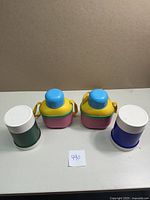 Photo of all four thermos items on table, showing two multi-colored food jar thermoses and two standard 10oz thermos jars.