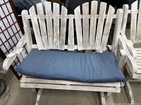 Two seat white washed wood gliding bench with navy blue cushion, slatted back