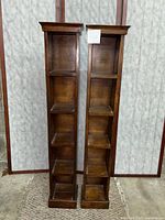 Front view showing two tall wooden shelving units with multiple compartments and visible wear.