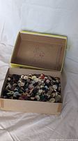 Cardboard box partially open showing hundreds of assorted vintage buttons inside.