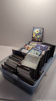 Multiple stacks of assorted Magic: The Gathering cards inside a transparent plastic bin, visible are many cards including some sleeved.