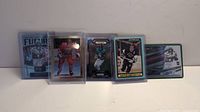 Five sports cards displayed in protective sleeves, including Wayne Gretzky and Breece Hall.