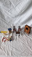 Full set of vintage dollhouse furniture items including chairs, coffee table, armoire, ironing board, washing machine box, and wooden toys.