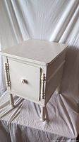 Full view of white wooden side table with decorative legs and closed door.