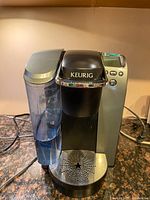 Front view of Keurig XL coffee maker showing water reservoir, dispenser, control panel, and drip tray.