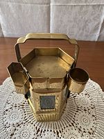 Close-up front view of brass Thai noodle cart figurine showing detailed etched brass and condiment holders.