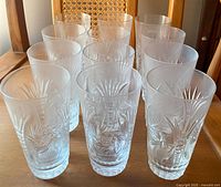 Front view showing 12 highball crystal glasses in pinwheel cut design arranged on table.