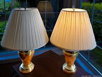 Both brass table lamps together, one lit and one unlit, showing overall design and proportion.