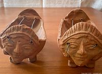 Front view of pair of Balinese clay hibachis showing facial end sculptures and wire grills