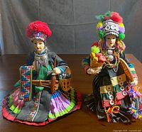 Front view of two Hill tribe dolls wearing traditional bright and detailed clothing, sitting on a table